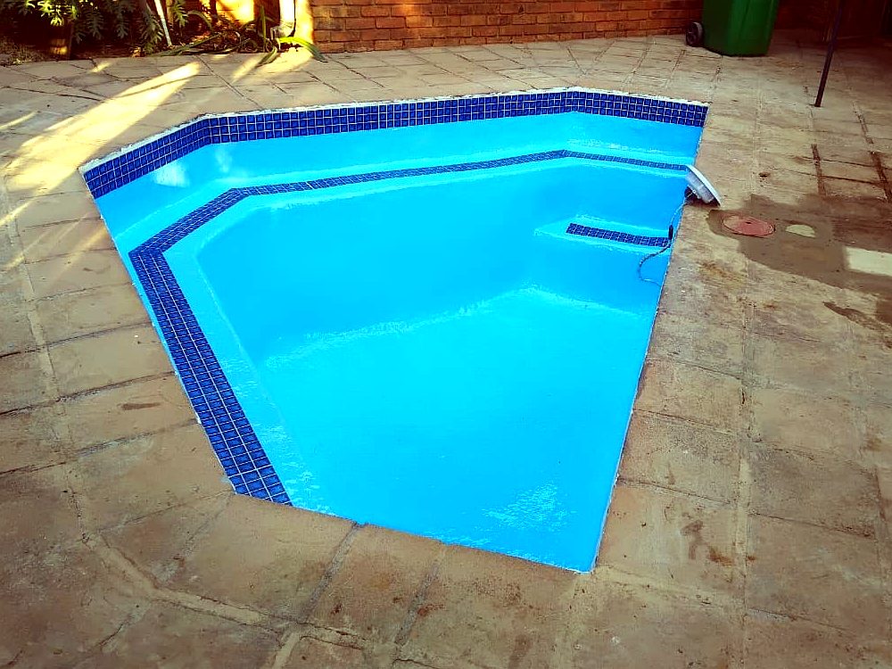 Same pool fully resurfaced and tiled, filled with blue finish — after