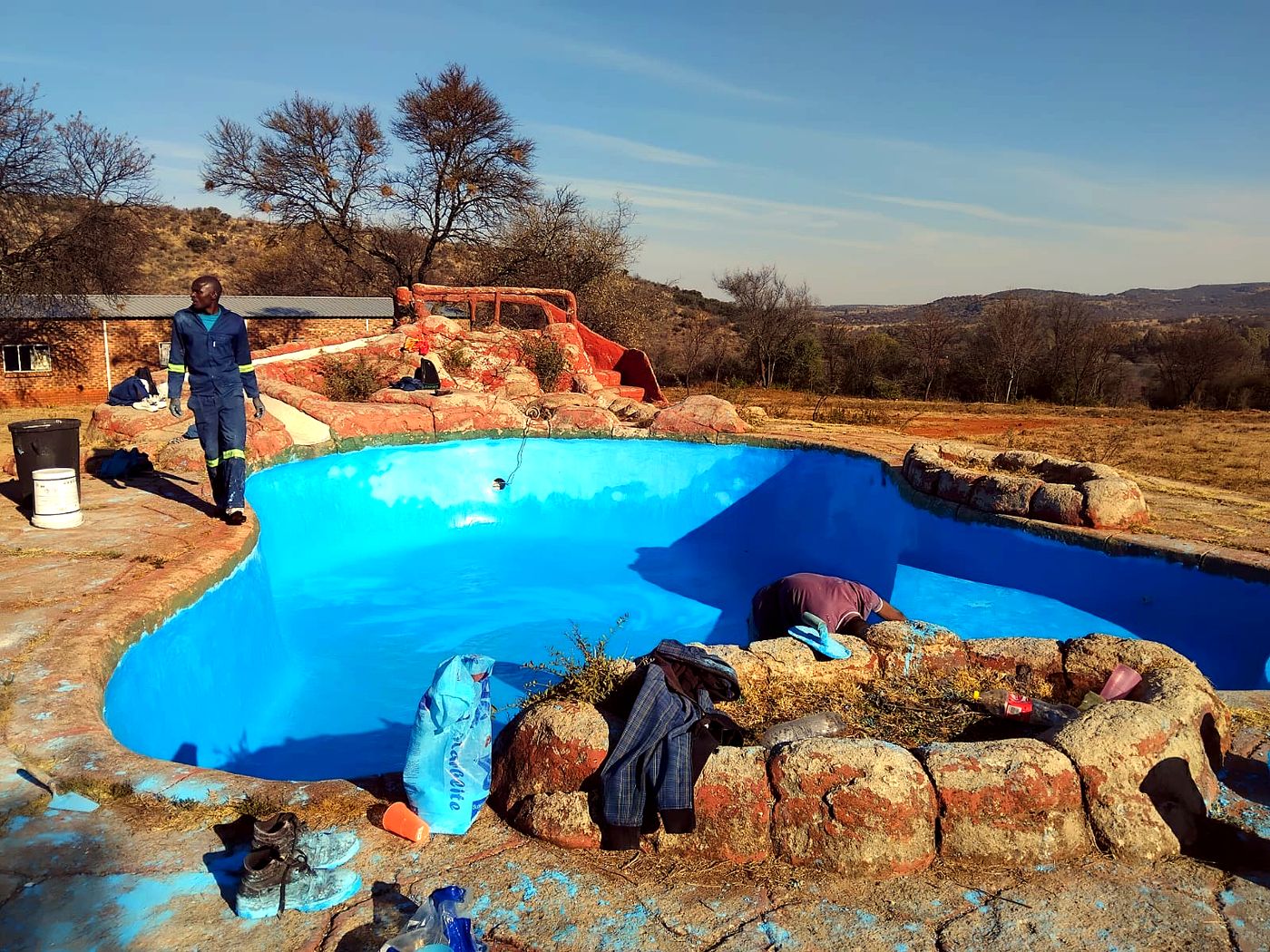 Team repainting a kidney-shaped farm pool